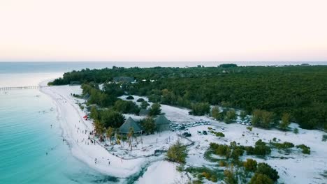 gran mosca de arriba a abajo tiro de drone de grúa de una fiesta en la playa al atardecer