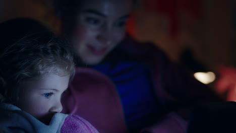 madre e hijo usando una computadora tablet madre enseñando a una niña pequeña jugando juegos en tecnología de pantalla táctil divirtiéndose antes de acostarse