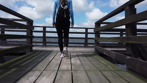 Toma-Cinematográfica-De-Una-Mujer-Caminando-En-Un-Muelle-De-La-Laguna-Y-Levantando-Los-Brazos-Con-Alegría-Al-Final