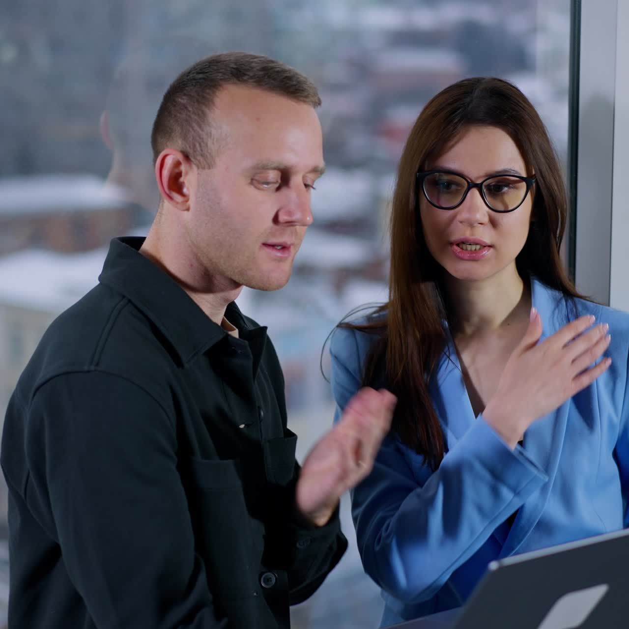 Partners are going to have video chat conference. People stand at the window holding laptop, smiling to camera. Blurred backdrop