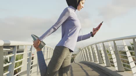 Mujer-Con-Hijab-Estirándose-Y-Escuchando-Música-Afuera.