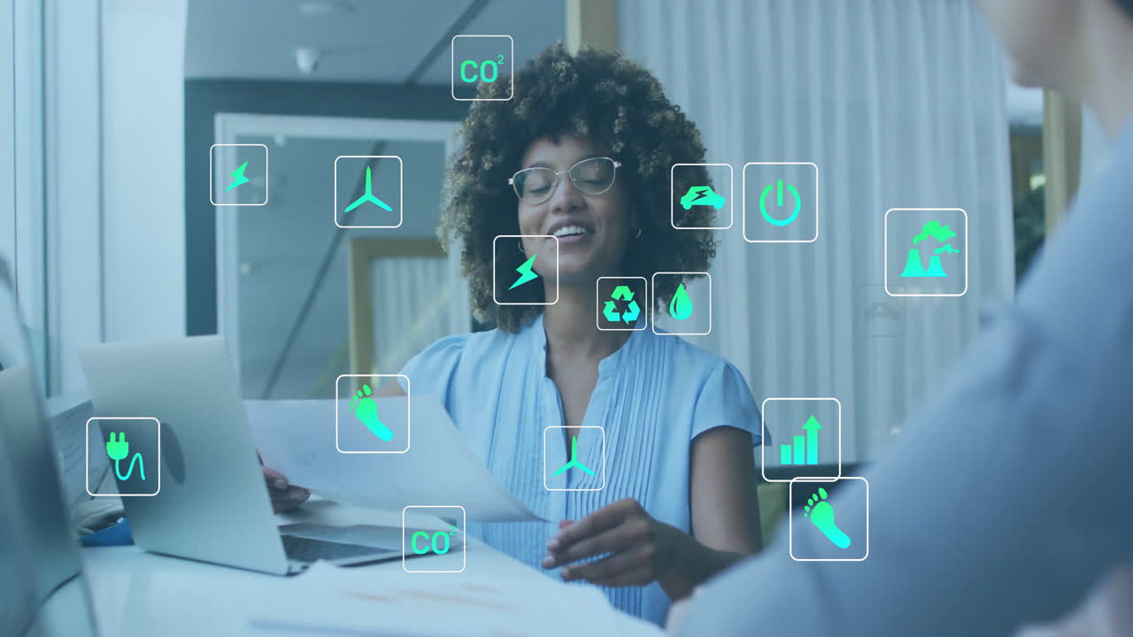 Animation of ecology icons over diverse colleagues using laptop and discussing work in office