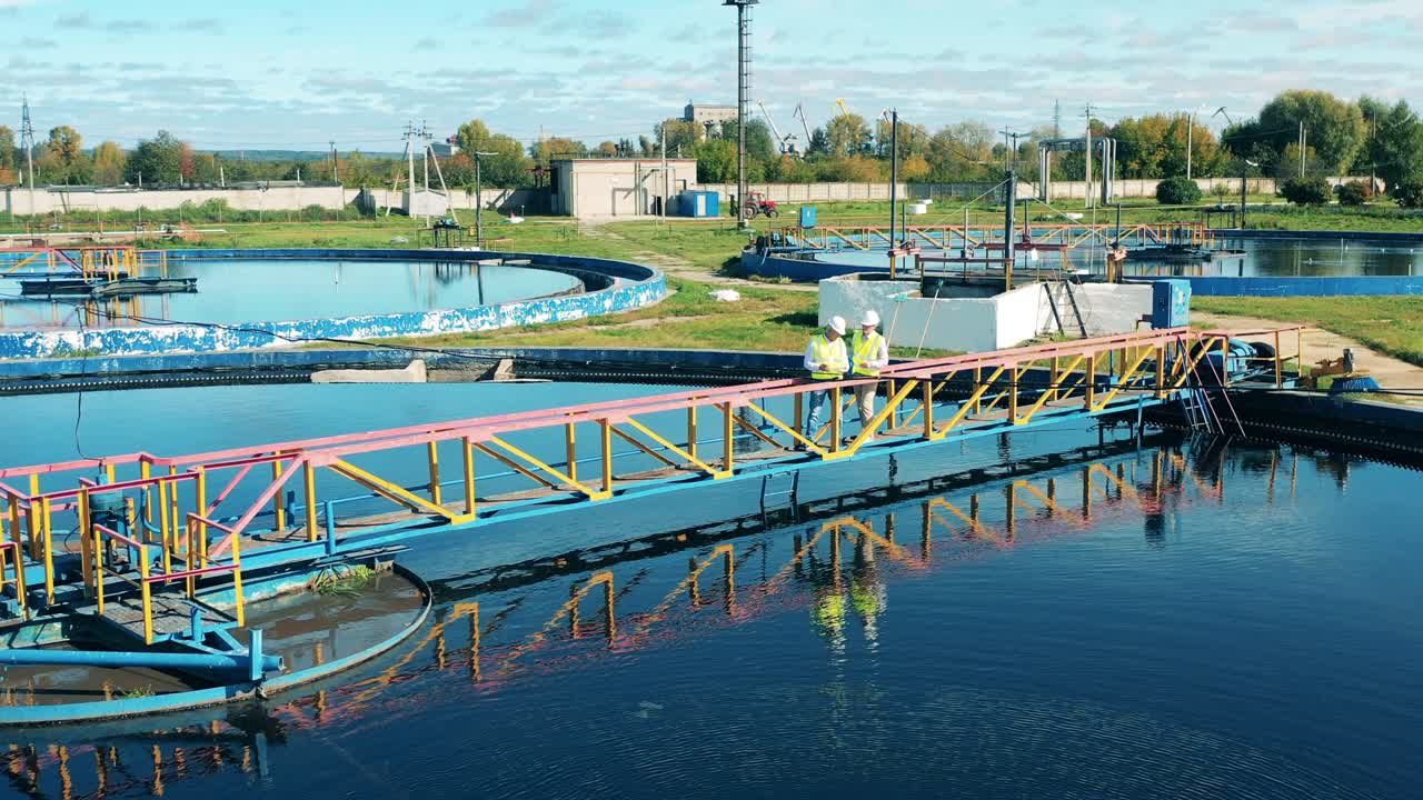 operadores masculinos de tratamiento de aguas residuales que inspeccionan un clarificador circular