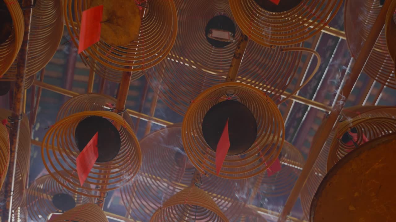 toma cinematográfica de inciensos circulares adheridos al techo ardiendo lentamente y difundiendo humo-1