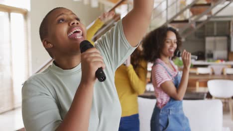 grupo diverso de amigas divirtiéndose cantando karaoke en casa