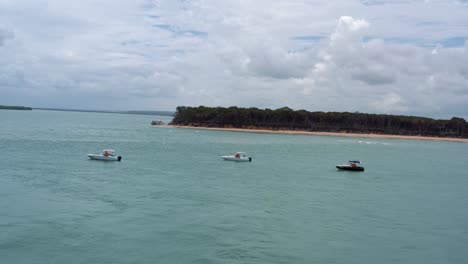 Right-trucking-left-panning-aerial-drone-shot-of-various-tourist-motorboats-docked-on-the-Guaraíras-Lagoon-with-the-Malembá-in-the-background-in-Rio-Grande-do-Norte,-Brazil-on-a-warm-sunny-summer-day