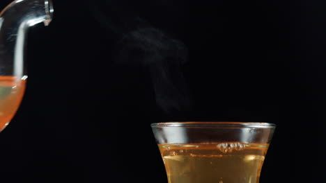 pouring hot tea from a glass teapot into a cup