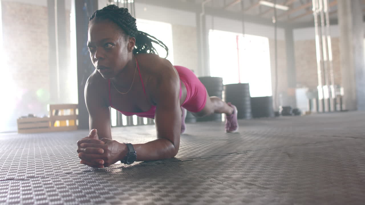 Planking on gym floor, woman in sportswear focusing on core strength workout, copy space