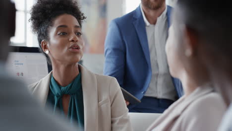 mujer de negocios de raza mixta charlando con colegas en una reunión de oficina teniendo una conversación compartiendo ideas en el lugar de trabajo corporativo