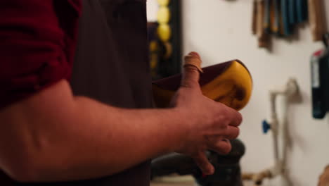 carpenter putting sandpaper on piece of plastic, creating abrasive sponge