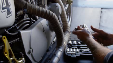 male mechanic repairing motorbike in repair garage 4k