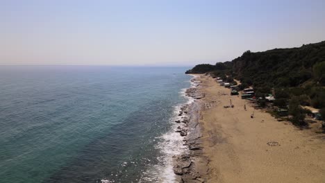 Aerial-drone-clip-moving-backwards-over-a-sandy-beach-in-Kavala,-Macedonia,-Greece