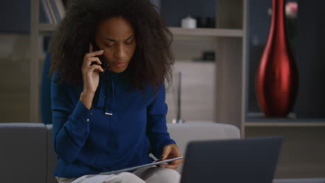 Serious-afican-american-ceo-woman-talk-phone-search-tablet-device-in-home-office