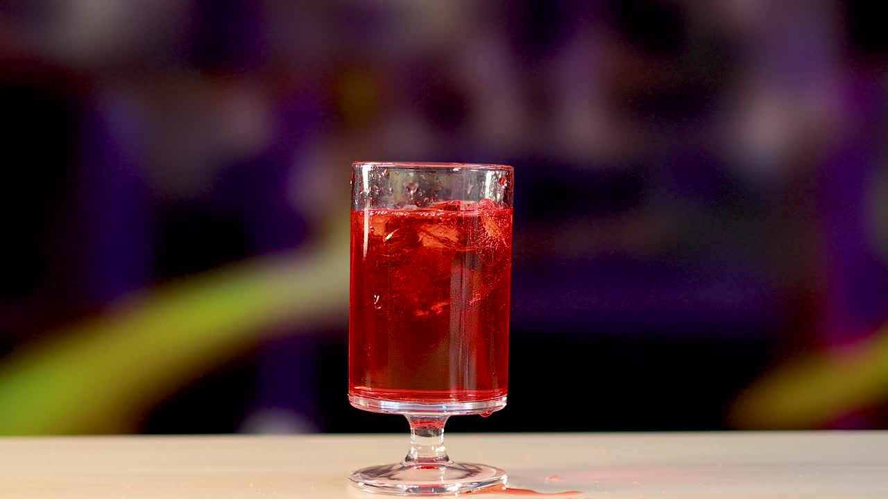 Red Negroni cocktail poured into a glass on a colorful background. Bright lighting highlights the drink's vivid hue