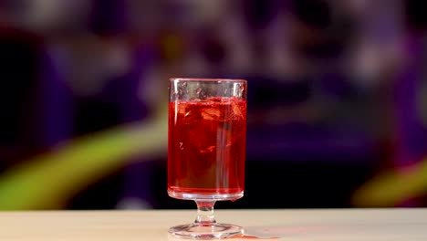 red negroni cocktail poured into a glass on a colorful background. bright lighting highlights the drink's vivid hue