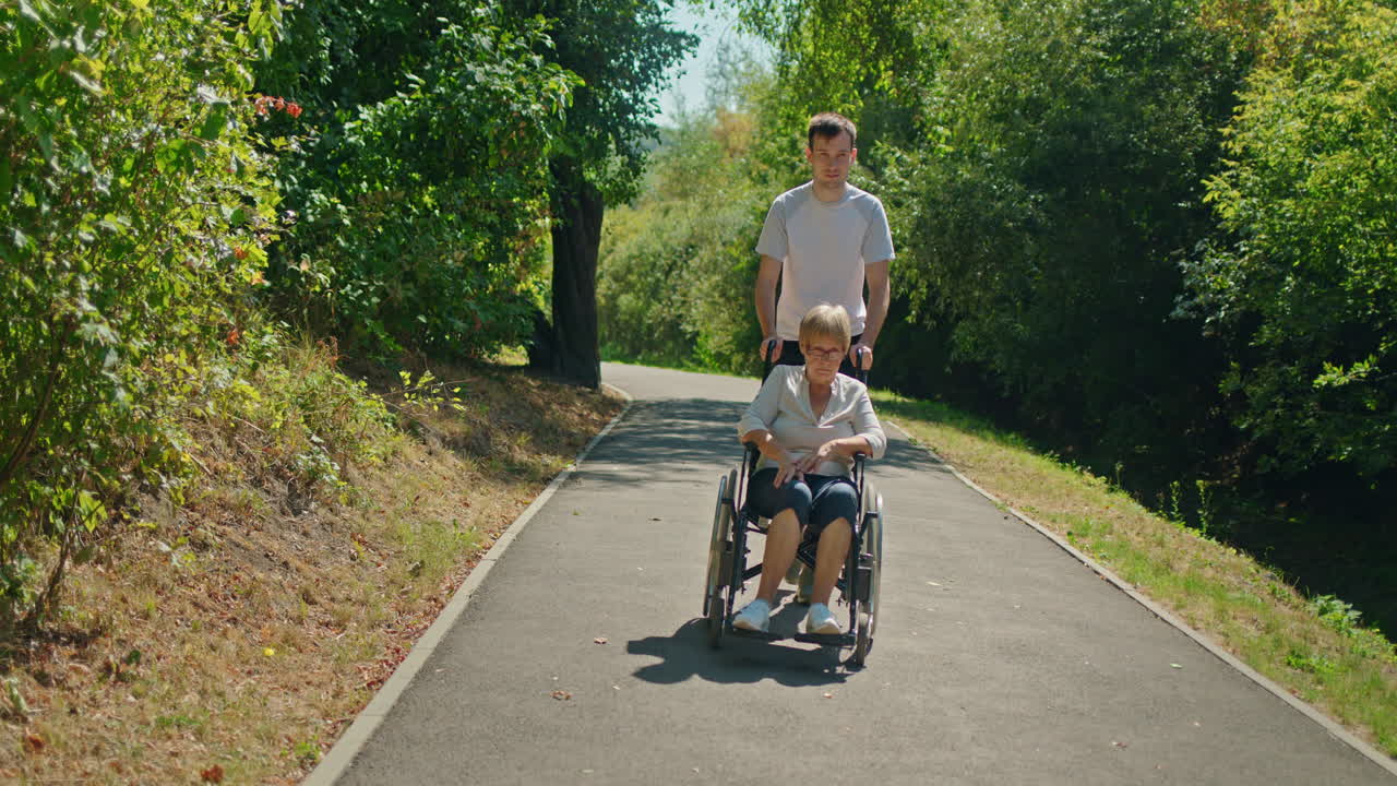 hombre ayudando a una anciana en silla de ruedas en un parque
