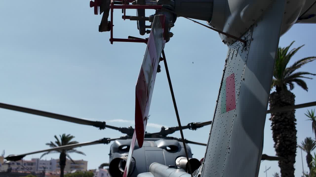 Close-up view of a military helicopter tail section under an outdoor sky.