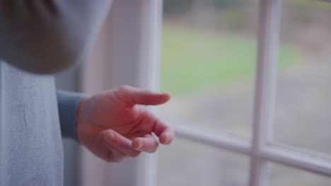 close up of man at home standing by window and drinking cup of coffee