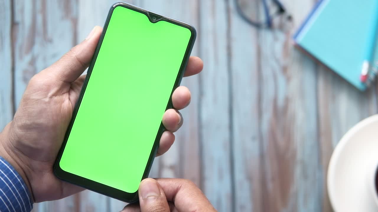 Vista superior de la mano del hombre con un teléfono inteligente en el escritorio de la oficina