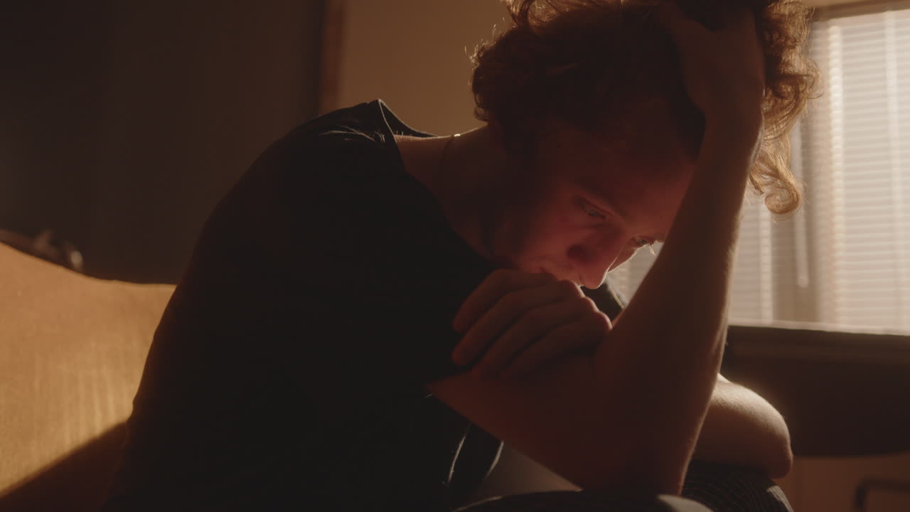 joven triste sosteniendo su cabeza, sufriendo de depresión en casa