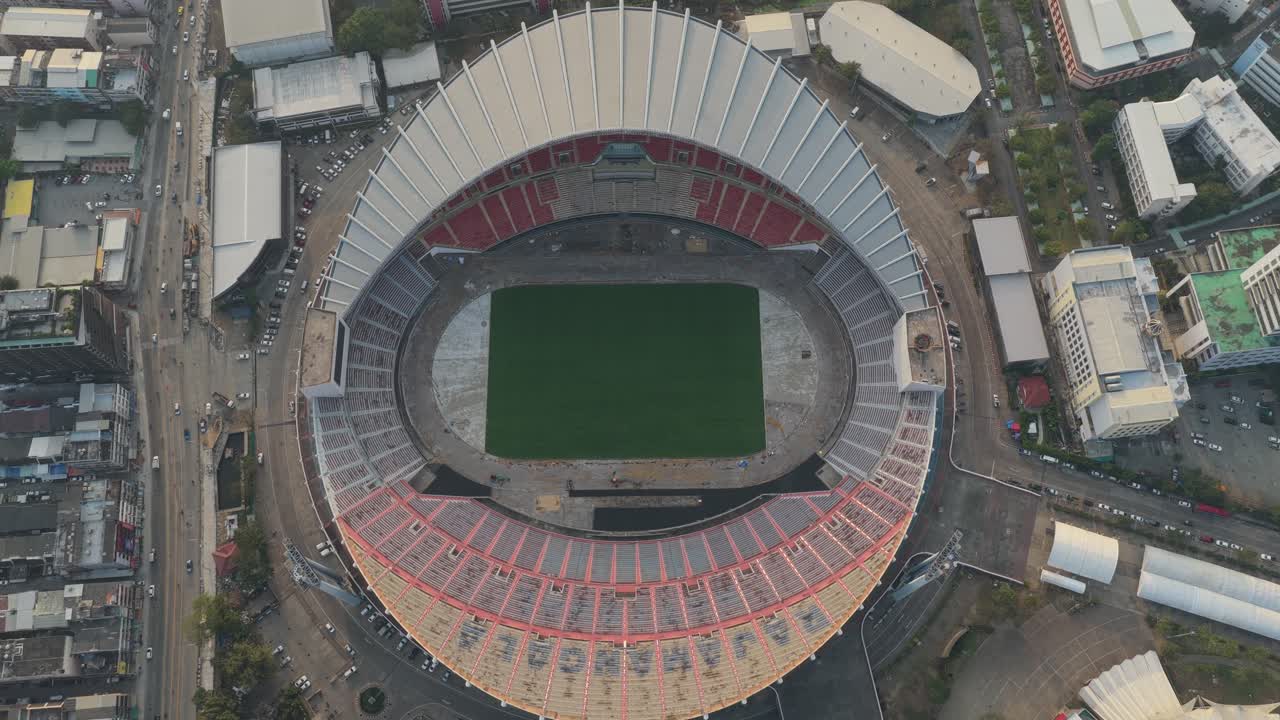 Drammatica vista aerea dall'alto dello Stadio Nazionale Rajamangala a Bangkok, Thailandia, che rivela la sua architettura e il paesaggio urbano circostante.