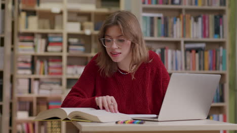 young female student researching in library using laptop