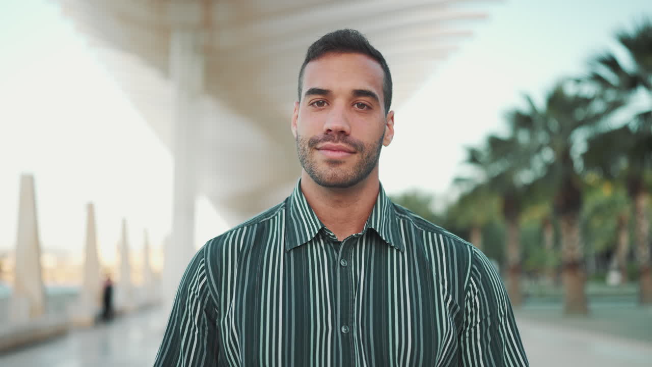 Young man smiling at the camera and walking outdoors.