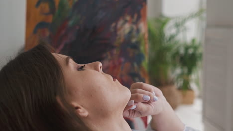 thoughtful lady touches chin by hand sitting in light room