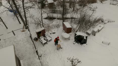 aerial shot of a canadian male in santa hat building a fire outside of his snow covered winter cabin