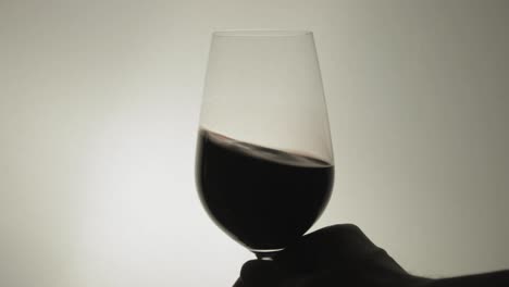 shaking a glass of wine with a hand in a steady position - close up shot