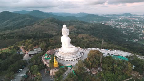 aerial panning view of the big buddha overlooking phuket town illuminated by the setting sun