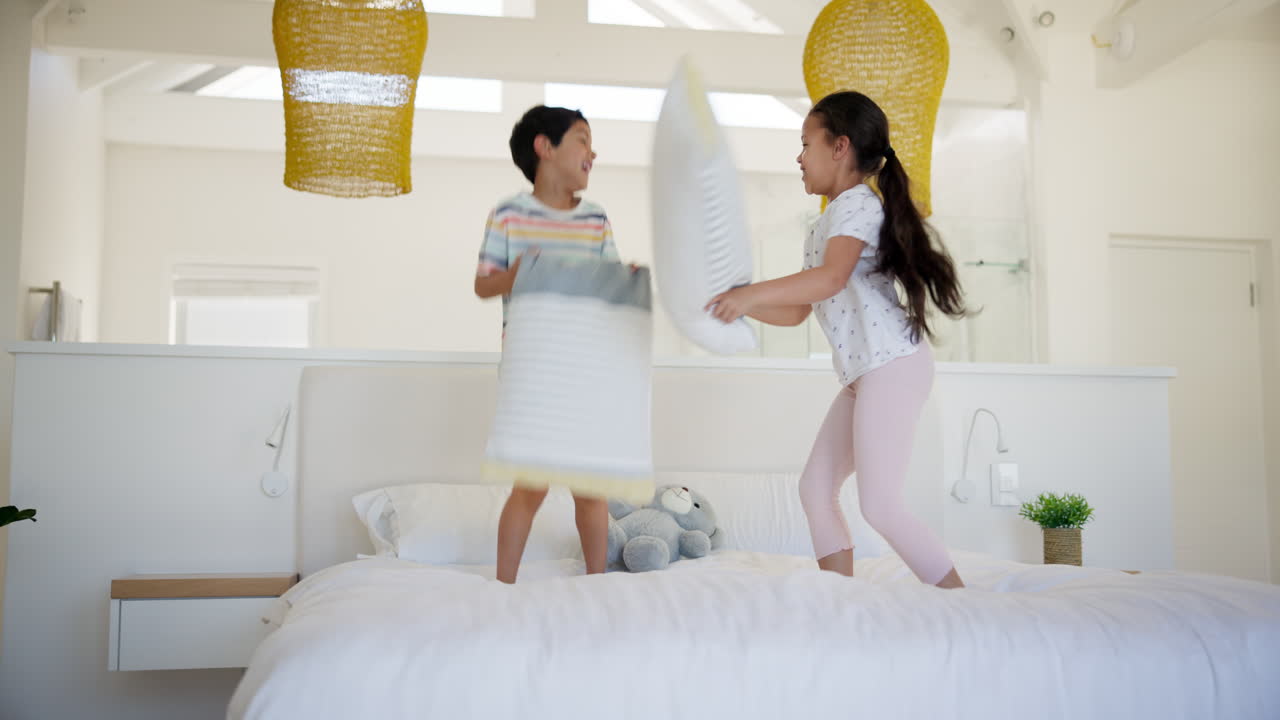 침실에서 베개 싸움을 하는 아이들