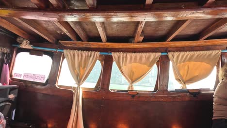 passenger inside a wooden boat with curtains and windows