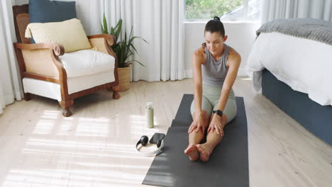 woman exercising on yoga mat at home, using fitness equipment and smartphone