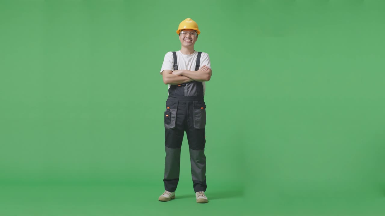 Full Body Of Asian Man Worker Wearing Goggles And Safety Helmet Smiling And Crossing His Arms While Standing In The Green Screen Background Studio