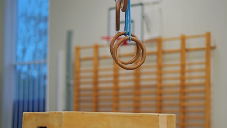 Two gymnastic rings hanging in empty School gymnasium, no people