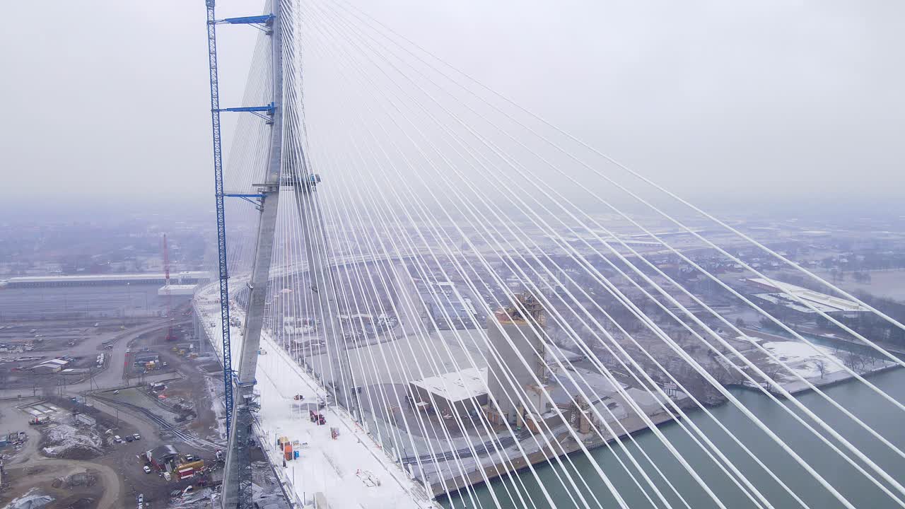 Aerial side view of Gordie Howe International Bridge cables covered in snow