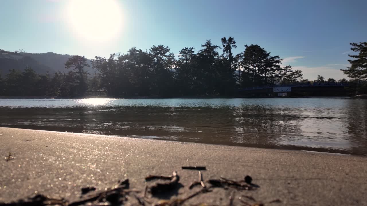 Sunlight glistening on the tranquil waters of Amanohashidate beach, enhancing the serene atmosphere of the peaceful shoreline