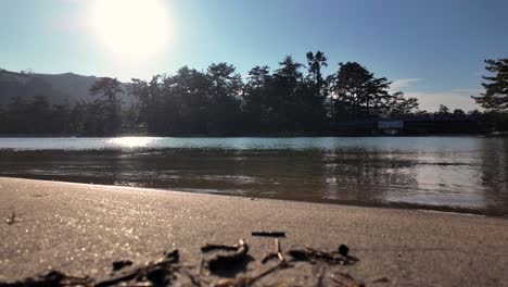 sunlight glistening on the tranquil waters of amanohashidate beach, enhancing the serene atmosphere of the peaceful shoreline