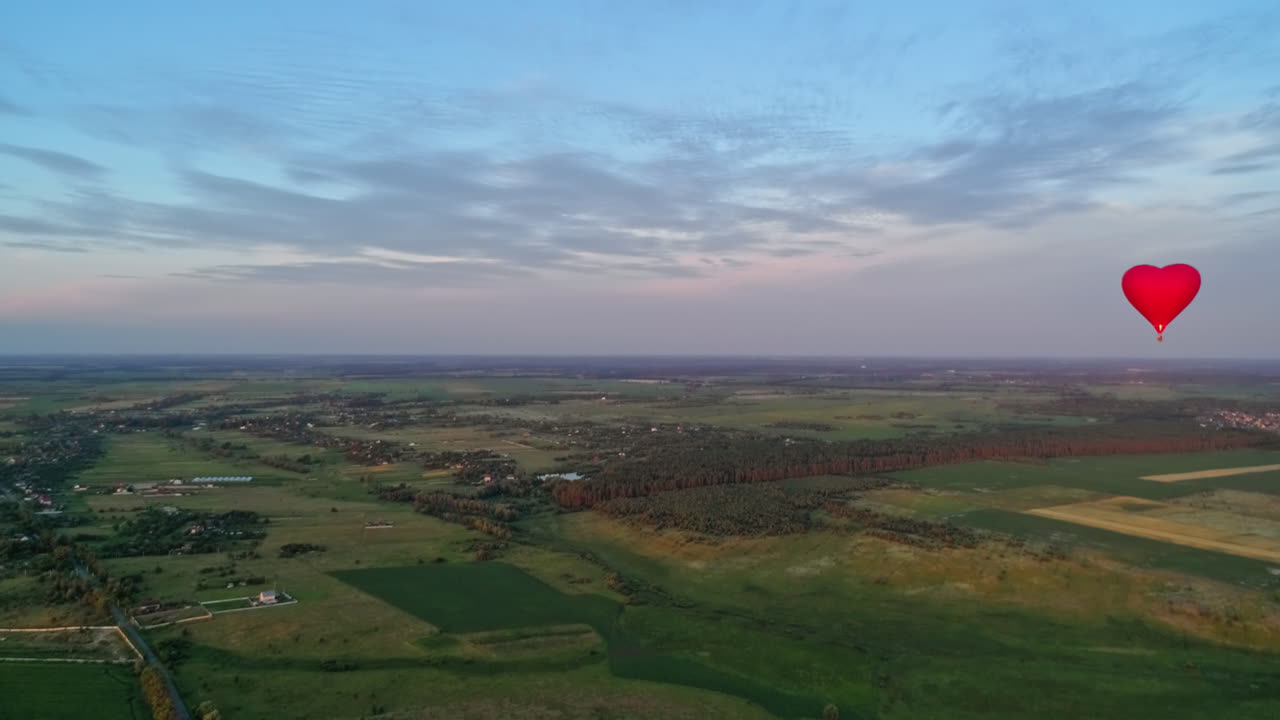 Summer landscape and aerostat in the air. Red hot air balloon flying over the green fields against the beautiful sky.