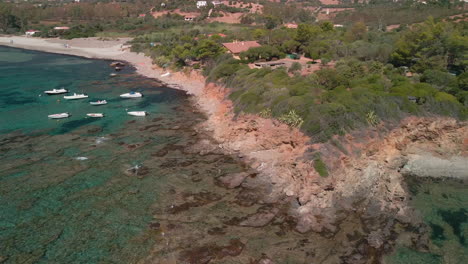 tropischer sommerstrand mit schnellbooten docken in der nähe der küste in dichter vegetation auf sardinien, italien an