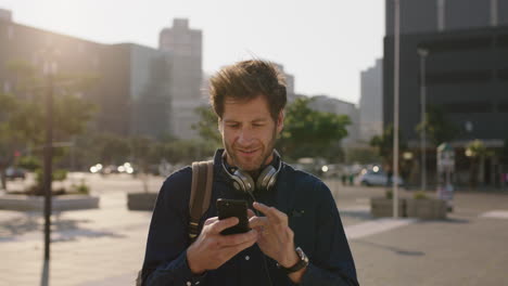 portrait of attractive caucasian man texting browsing using smartphone mobile app in city at sunset