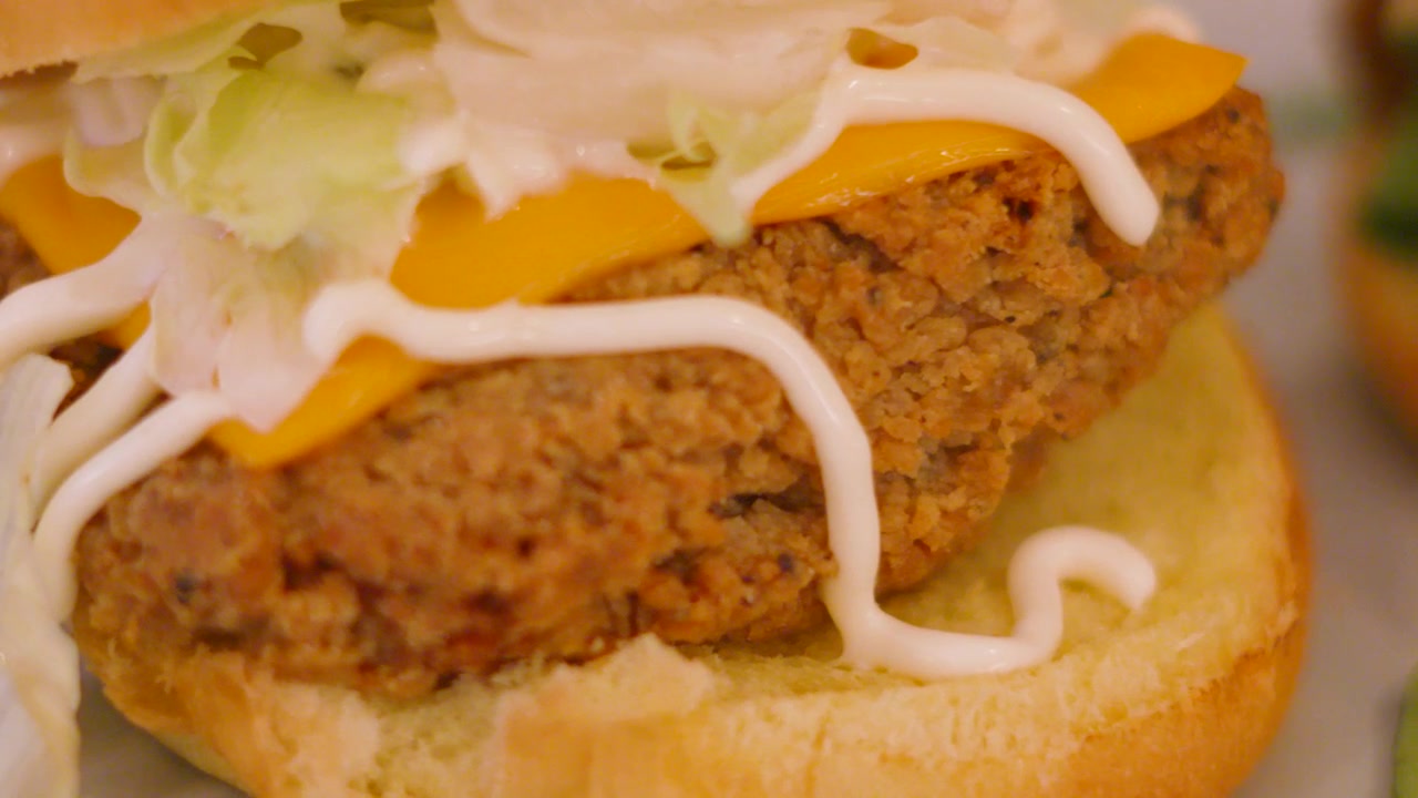 Primo piano di un hamburger di pollo fritto alla meridionale con formaggio, lattuga e maionese. Gustoso cibo spazzatura.