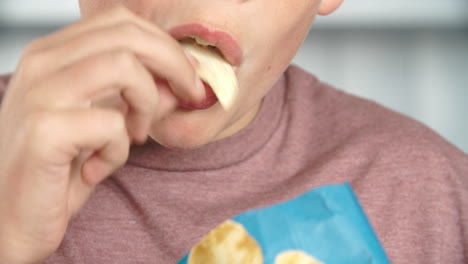 close up of boy eating packet of potato chips