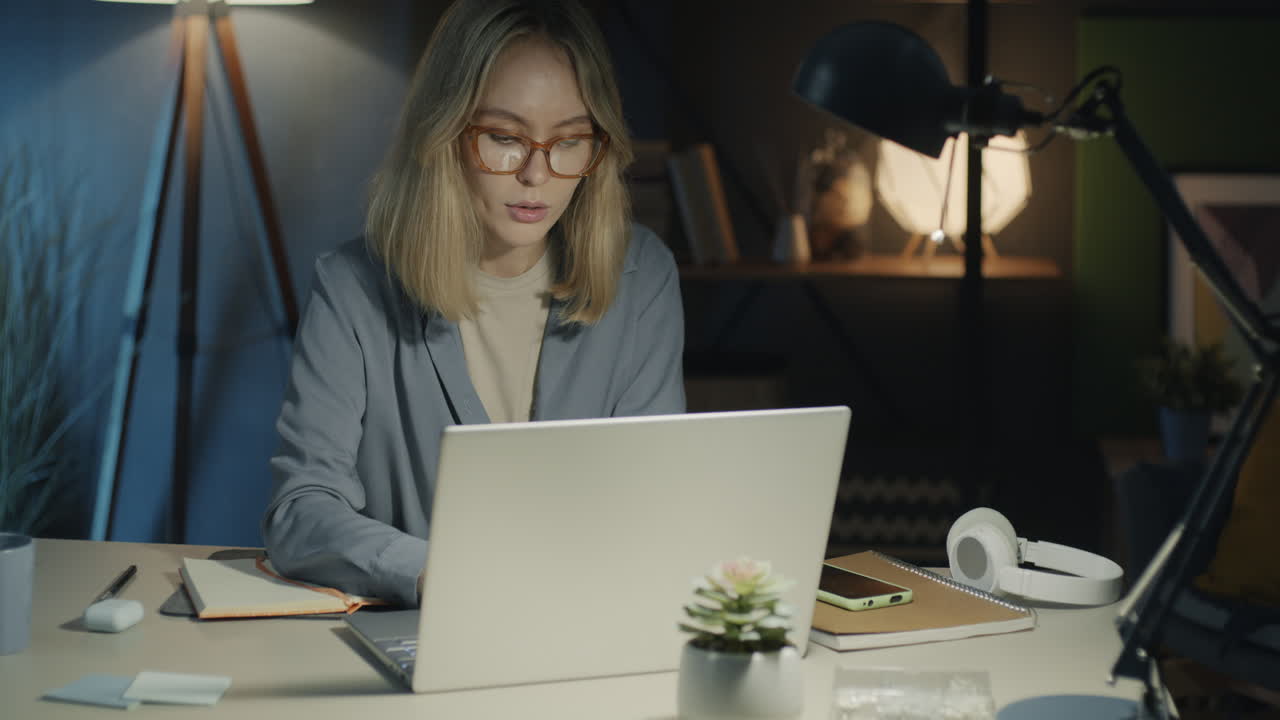 Woman working late at night on laptop in home office