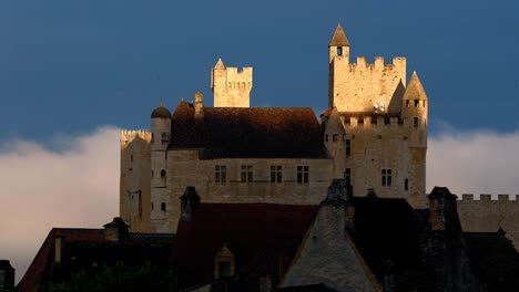 Time-lapse-of-the-Chateau-de-Beynac,-a-cliff-side-chateau-in-the-Dordogne-region,-clouds-pass-behind-the-building,-light-gradually-illuminates-the-stones-of-the-building,-France,-summer-sunrise