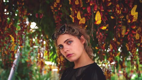 4K-UHD-Cinemagraph-of-a-young-brunette-woman-standing-next-to-a-beautiful-colorful-tree-with-a-lot-of-flower-blossoms-moving-around-her-head