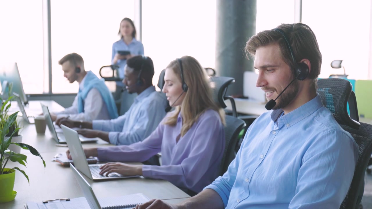 Diverse Call Center Team Working on Laptops with Headsets in Modern Office