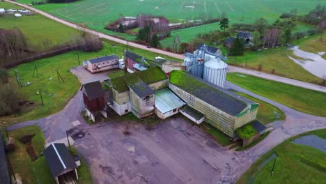 Rural Latvian grain facility, Soviet and modern structures, cloudy winter sky