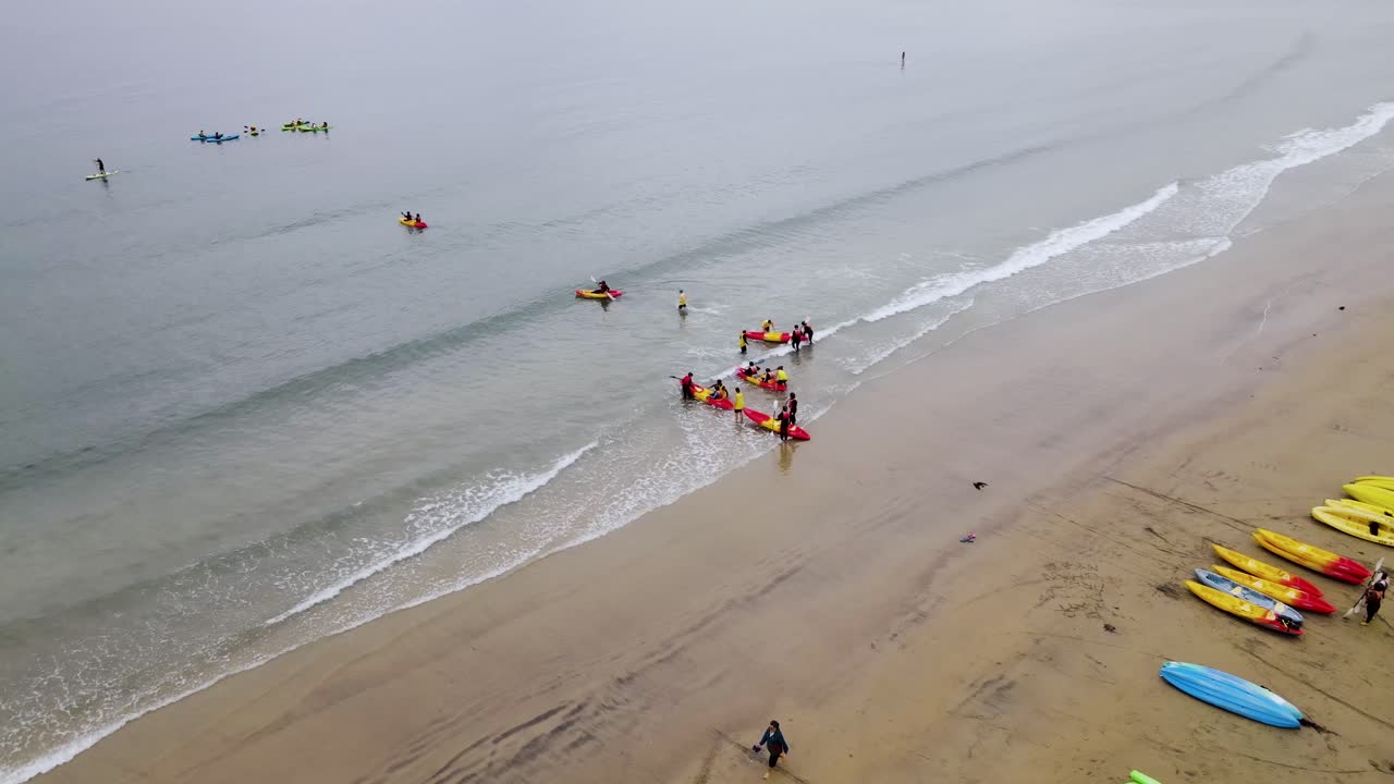 Bird's eye view of kayakers pushing off from beach in La jolla california, calm day